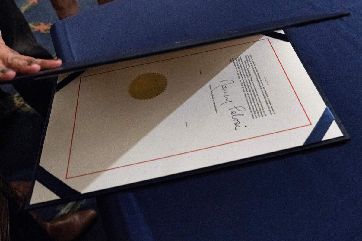 An aide closes the article of impeachment against President Donald Trump, after it was signed by House Speaker Nancy Pelosi of Calif., in an engrossment ceremony before transmission to the Senate for trial on Capitol Hill, in Washington, Wednesday, Jan. 13, 2021. (AP Photo/Alex Brandon)