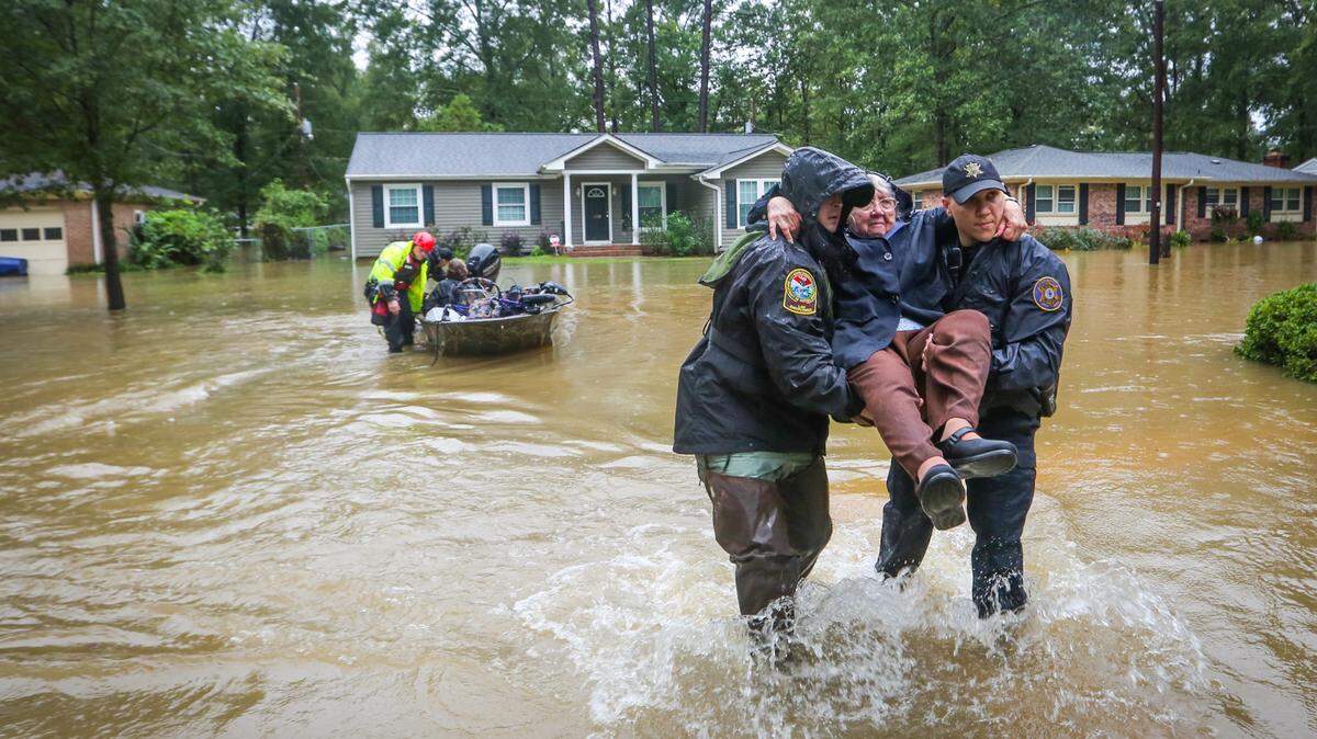 Officers carry June Loch to dry land after she was rescued from her home in the Pine Glen subdivision of Columbia, S.C. on Oct. 5, 2015. Record rainfall that October triggered floods that killed at least 19 people in South Carolina and caused extensive damage to neighborhoods that had never flooded before. Despite that disaster, only 9 percent of South Carolina households had purchased flood insurance by May of last year.