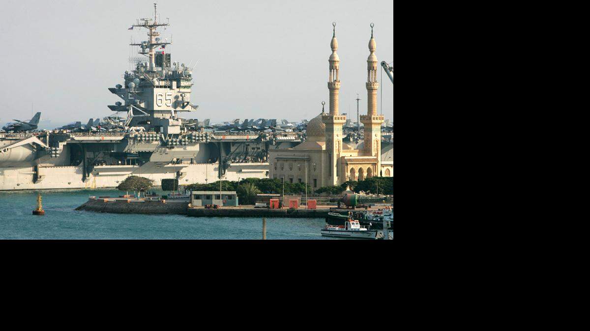 The USS Enterprise passes behind a mosque as it makes its way through the Suez canal Aug. 1. It replaced two carriers in a deployment aimed at sending a signal of strength to Iran.