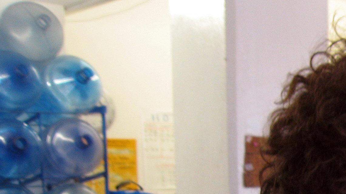 A worker at the small Agua Azul bottled water plant places the cap on a jug of purified water.