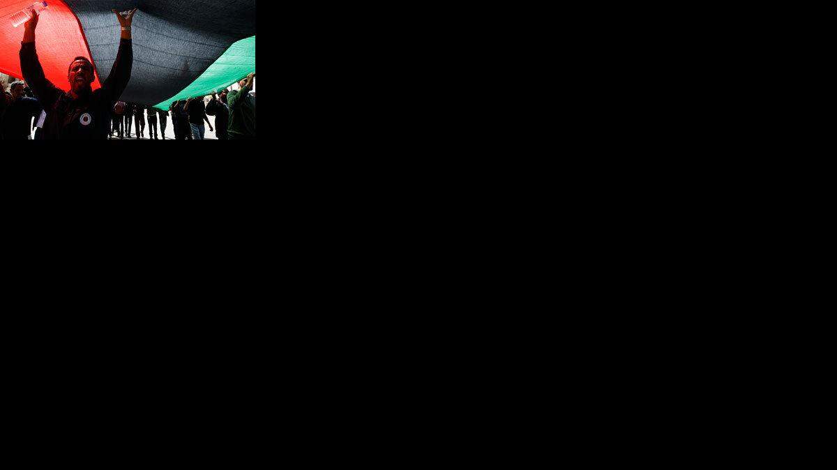 Demonstrators carry a large Libyan revolutionary flag to the Benghazi, Libya, courthouse.
