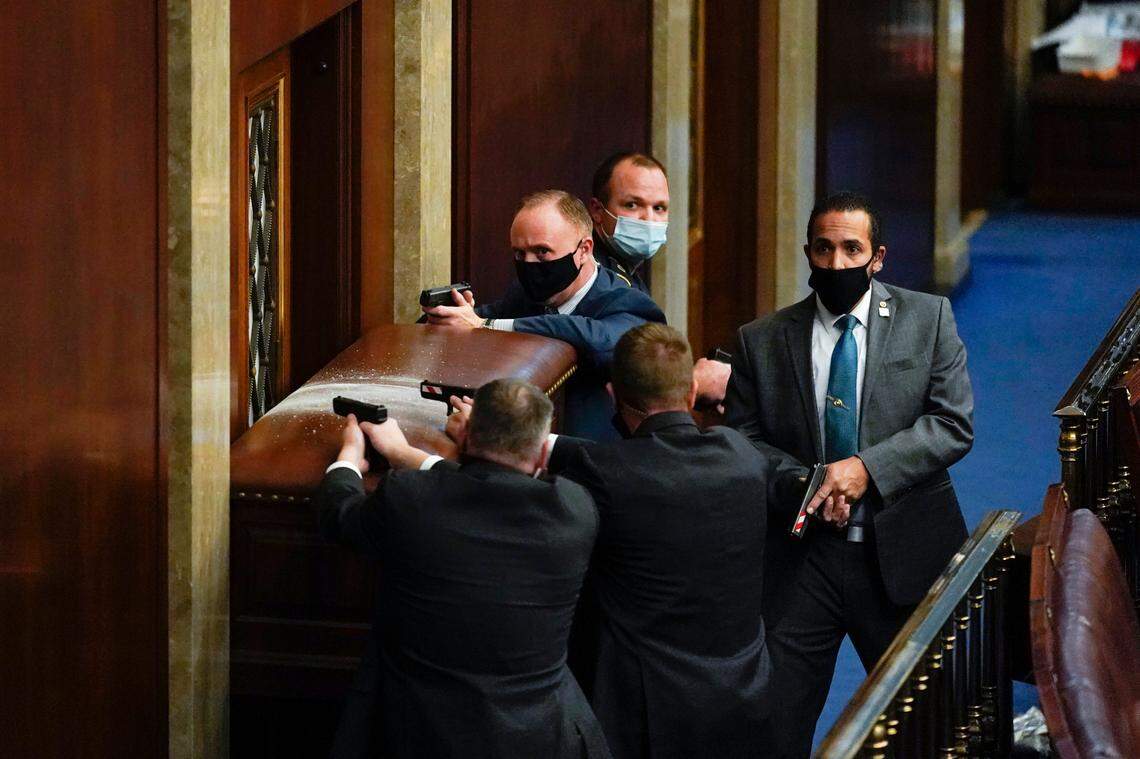 U.S. Capitol Police with guns drawn stand near a barricaded door as protesters try to break into the House Chamber at the U.S. Capitol on Wednesday, Jan. 6, 2021, in Washington. (AP Photo/Andrew Harnik)
