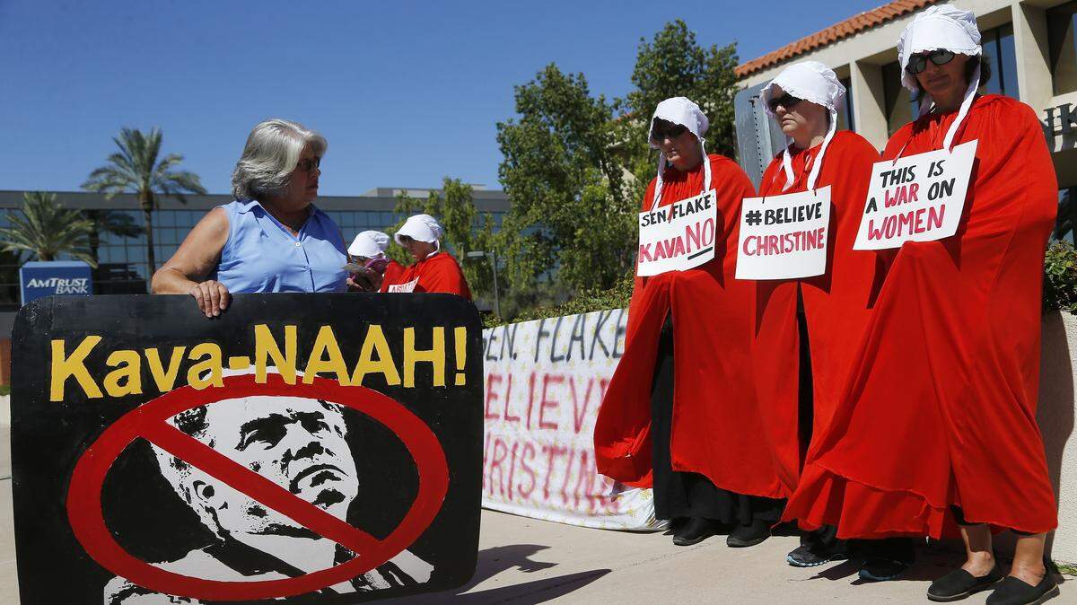 Members of the Handmaid’s Resistance AZ join another demonstrator in front of Republican Sen. Jeff Flake’s, R-Arizona, office as they protest the Supreme Court nominee Brett Kavanaugh Thursday, Sept. 27, 2018, in Phoenix, Arizona.