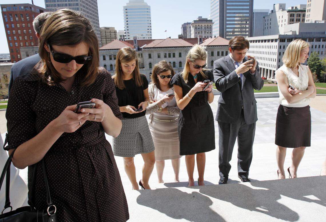 In this 2010 photo, staff members in the administration of Virginia Gov. Bob McDonnell, including Generra Peck (third from left), check their mobile devices during a press conference at the State Capitol in Richmond, Va., Wednesday, March 31, 2010. (AP Photo/Richmond Times-Dispatch, Bob Brown).