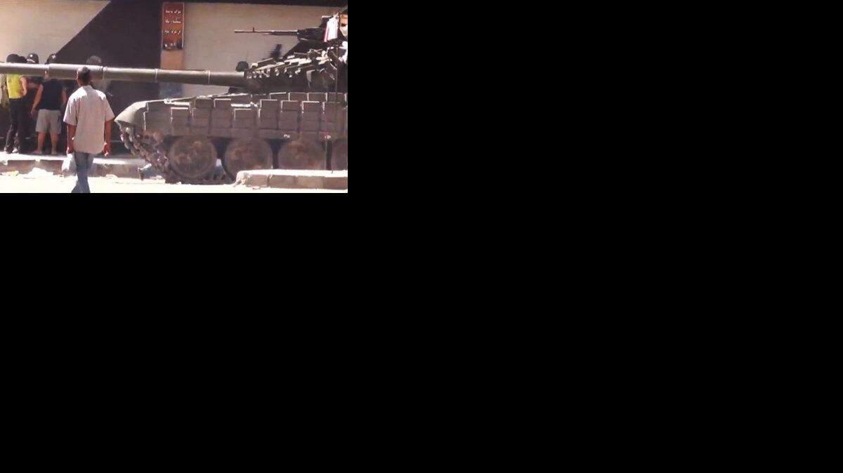 In this image made from amateur video, a man purportedly walks past a Syrian tank in Damascus.