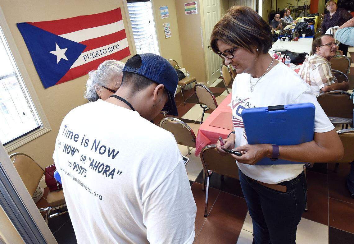 Mi Familia Vota (My Family Votes) representatives Jose Castellanos, left, and Naloy Zapata register voters during the Hispanic Heritage Celebration breakfast at the Kingdom of God Church in Orlando in 2016.