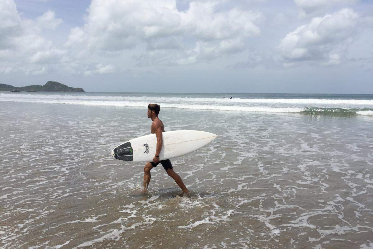 A surfer walks along the beach at Playa Colorado, a popular surfing spot along Nicaragua’s Pacific Coast. Except for a few surfers, tourism has declined sharply amid a wave of unrest in Nicaragua.