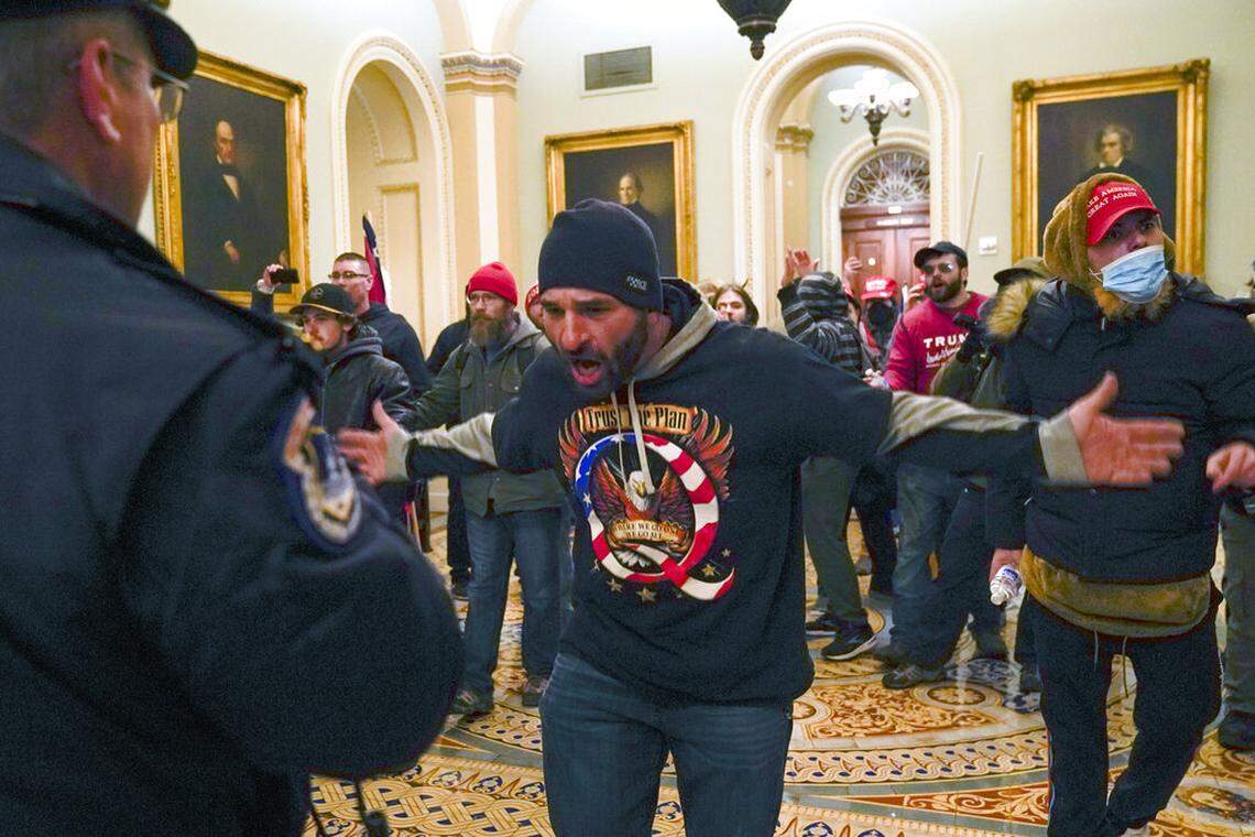 Rioters in support of President Donald Trump gesture to U.S. Capitol Police in the hallway outside of the Senate chamber at the Capitol in Washington, Wednesday, Jan. 6, 2021.