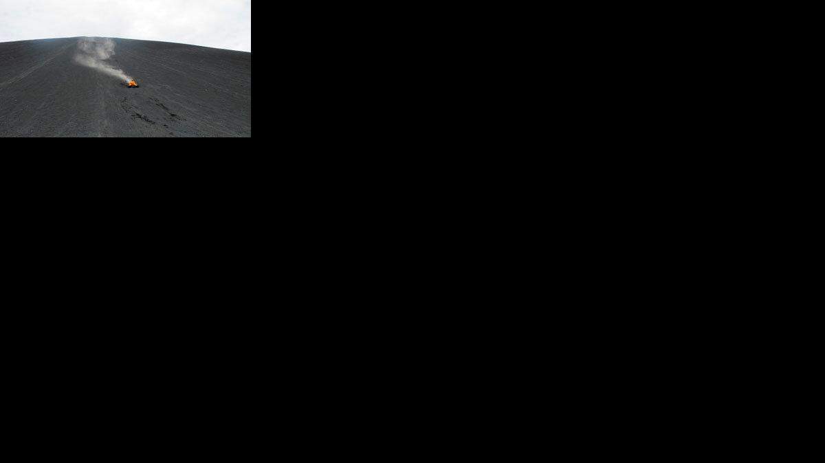A plume of cinder and volcanic ash trail behind a man on a toboggan descending Cerro Negro. It's called 'volcano boarding' and you'd better be brave to do it.