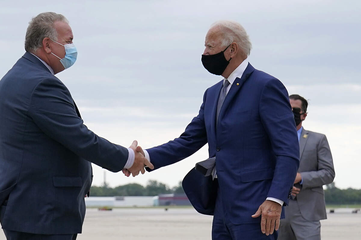 Democratic presidential candidate former Vice President Joe Biden shakes hands with advance staffer Brian McPartlin as he arrives at General Mitchell International Airport on Thursday, Sept. 3, 2020, in Milwaukee. (AP Photo/Carolyn Kaster)