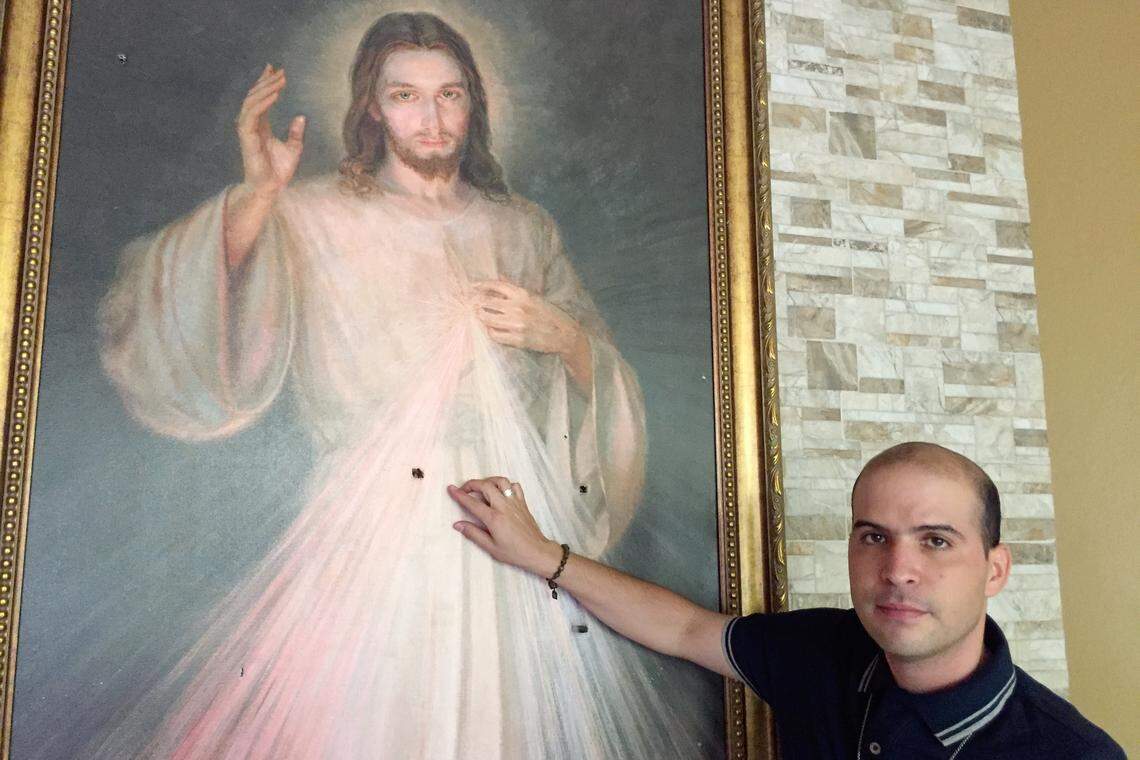 The Rev. Erick Alvarado, a vicar at Managua’s Divine Mercy Catholic Church, points to bullet holes in a religious painting. The church suffered a violent attack July 13-14, part of an assault by forces supporting beleaguered President Daniel Ortega against civilians demanding his removal.