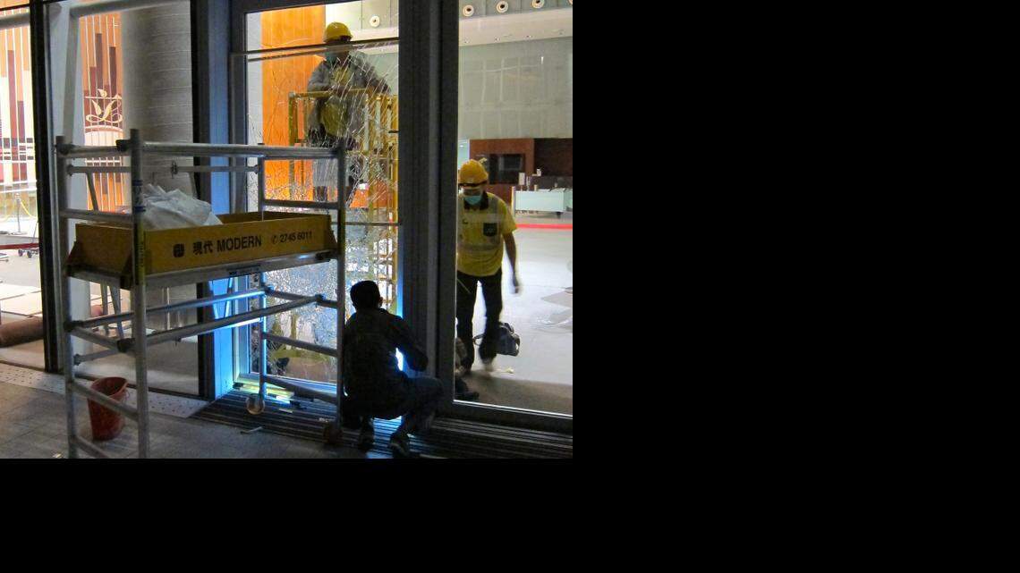 Workers repair a window at Hong Kong’s legislative building that protesters smashed early Wednesday. Six people were arrested and four officers injured in the first serious incident at the ongoing protests in China in weeks.
