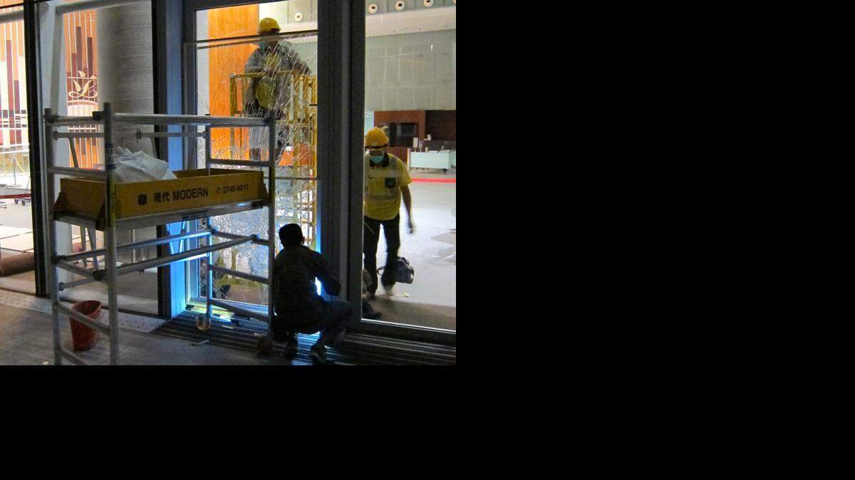 Workers repair a window at Hong Kong’s legislative building that protesters smashed early Wednesday. Six people were arrested and four officers injured in the first serious incident at the ongoing protests in China in weeks.
