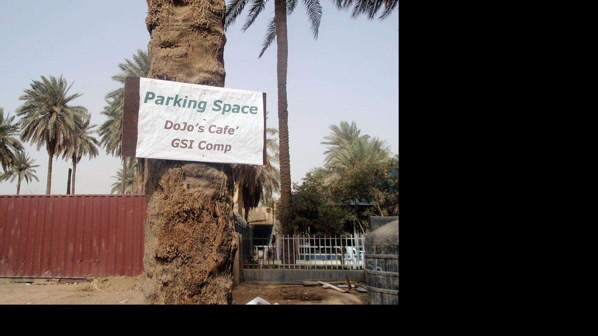 A sign for the DoJo Baghdad Cafe serving coffee and donuts to soldiers diplomats and anyone else in the Green Zone is posted on a nearby tree.