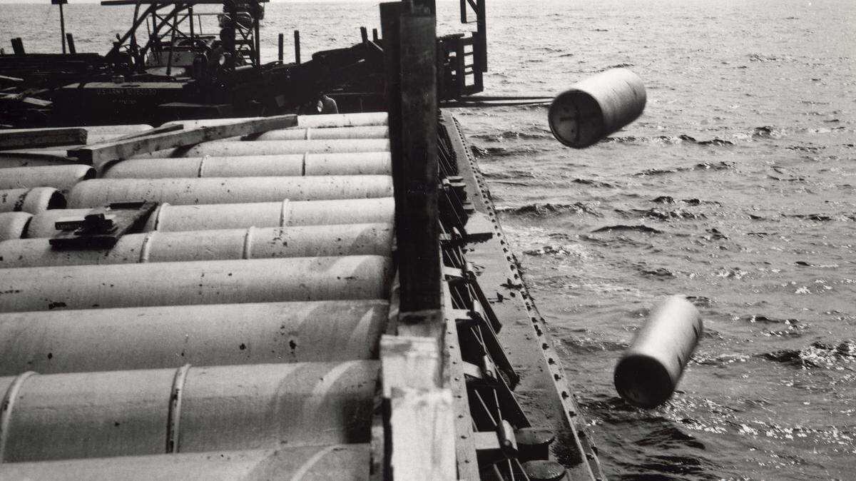 In this 1964 file photo provided by the U.S. Army, a forklift shovels one-ton containers of mustard gas over the side of a barge somewhere in the Atlantic Ocean. In 2005, a witness, Ellis R. Cole, said the Army also dumped radioactive waste along with chemical weapons off Virginia in 1960. (AP Photo/U.S. Army via Daily Press)