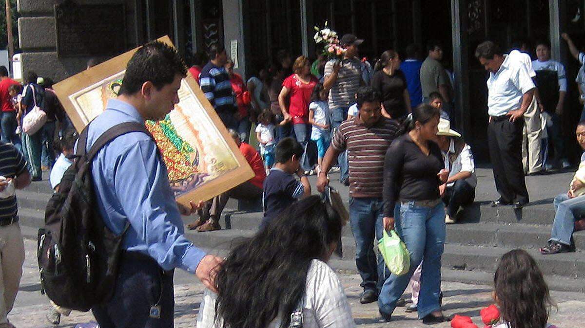 A woman walks on her knees, with her family beside her, towards the Basilica of Guadalupe to ask for blessings from the Virgin de Guadalupe.