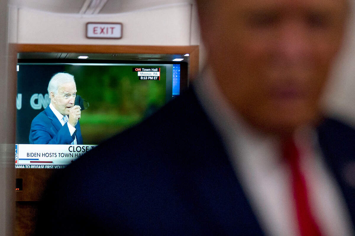 A television screen shows Democratic presidential candidate former Vice President Joe Biden holding up a mask, as President Donald Trump talks with reporters on Air Force One while returning to Washington after a campaign rally at Central Wisconsin Airport, Thursday, Sept. 17, 2020. (AP Photo/Evan Vucci)