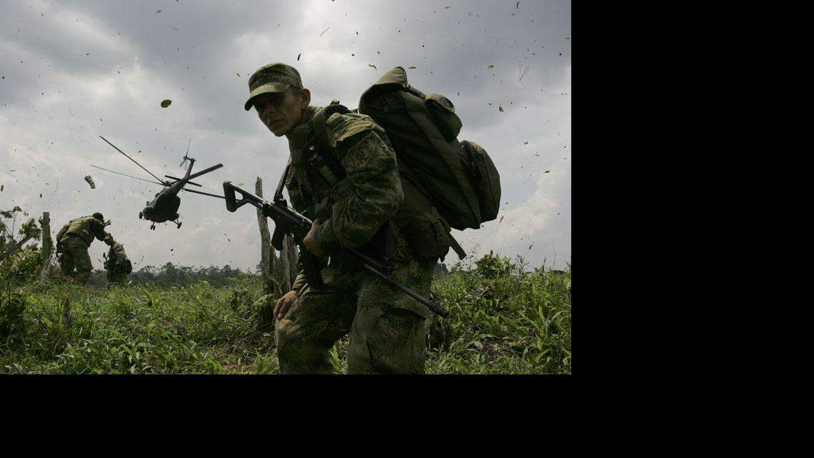 A Colombian soldier guards a helicopter landing zone near a coca field.