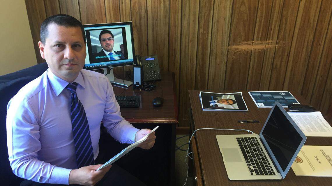 Venezuelan prosecutor in exile Pedro Lupera is shown in his office in Washington, D.C., on July 29, 2019. Lupera is holding a photo of his protege Luis Sanchez, who was arrested on Aug. 11, 2017, after Lupera was forced to flee the Maduro regime.
