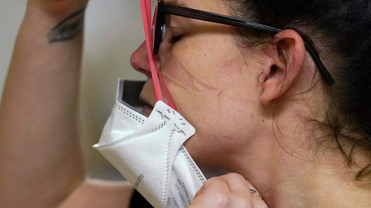 FILE - Registered nurse Jessalynn Dest pulls on a new N95 mask as indentations remain from another she had just removed after leaving a COVID-19 patient room in the acute care unit of Harborview Medical Center, Jan. 14, 2022, in Seattle. The Biden administration will begin making 400 million N95 masks available for free to Americans starting next week, now that federal officials are emphasizing their better protection against the omicron variant of COVID-19 over cloth face coverings. The White House announced Wednesday that the masks will come from the government’s Strategic National Stockpile, which has more than 750 million of the highly protective masks on hand. (AP Photo/Elaine Thompson, File)