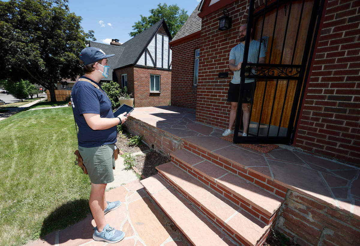 In this Wednesday, June 24, 2020, photo, Joey Prestley, a staff canvasser for the Progressive Turnout Project, left, talks to Scott Gifford while reaching out to voters in the age of the new coronavirus in northwest Denver. The coronavirus pandemic isn’t going away anytime soon, but campaigns are still forging ahead with in-person organizing. (AP Photo/David Zalubowski)
