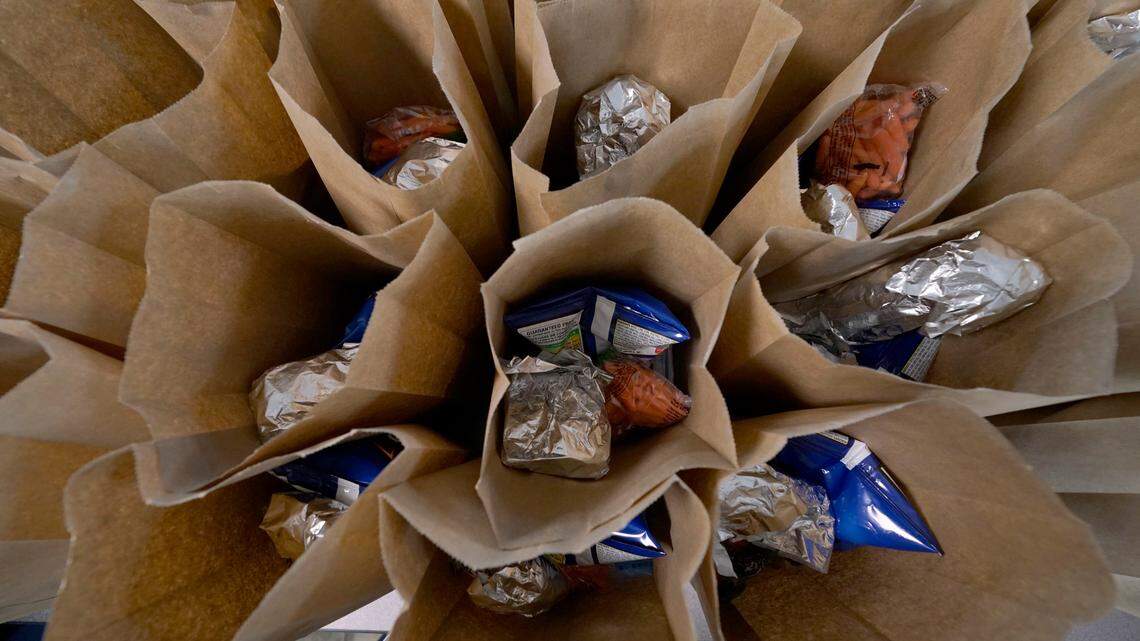 Bagged lunches await stapling before being distributed to students. The Biden administration on Monday announced efforts to provide funding for food for more than 30 million children over the summer.