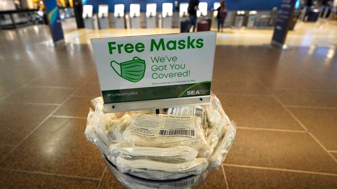 A sign near check-in counters at Seattle-Tacoma International Airport offers free masks to travelers, Monday, March 1, 2021, in Seattle. (AP Photo/Ted S. Warren)