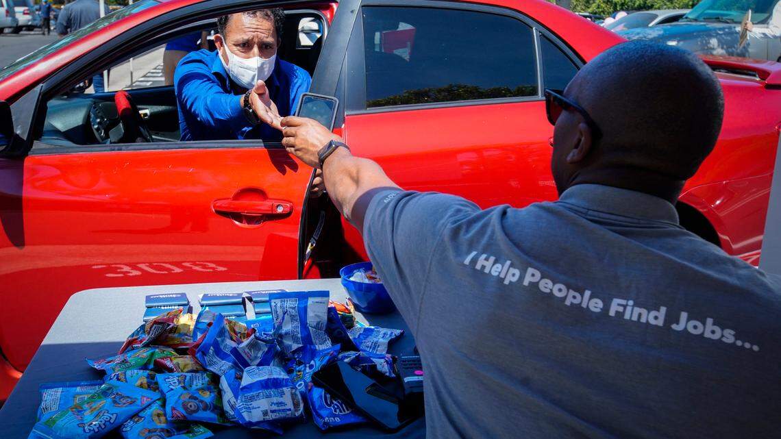 Brandon Earl, right, helps David Lenus, a job seeker, fill out an application at a drive up job fair for Allied Universal in Gardena, Calif., in May.