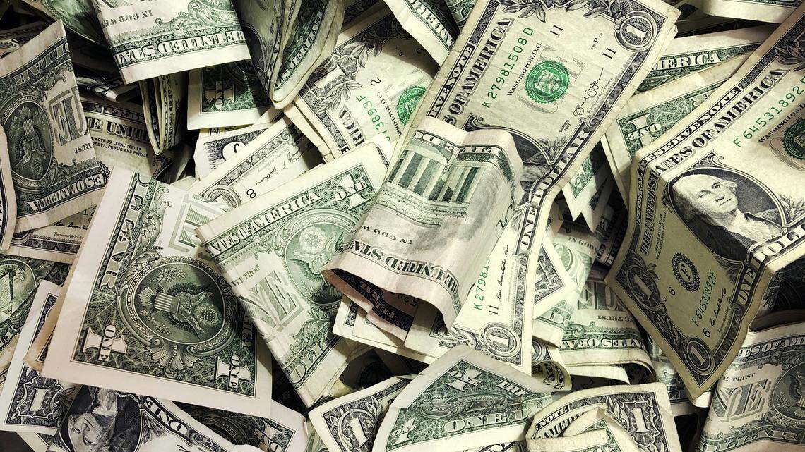 In this Jan. 21, 2020 file photo, dollar bills have been dropped into a tip jar at a car wash in the Brooklyn borough of New York. An Arizona couple is accused of fraudulently using federal money to buy multiple properties, including a $1.3 million Gilbert home, feds say.