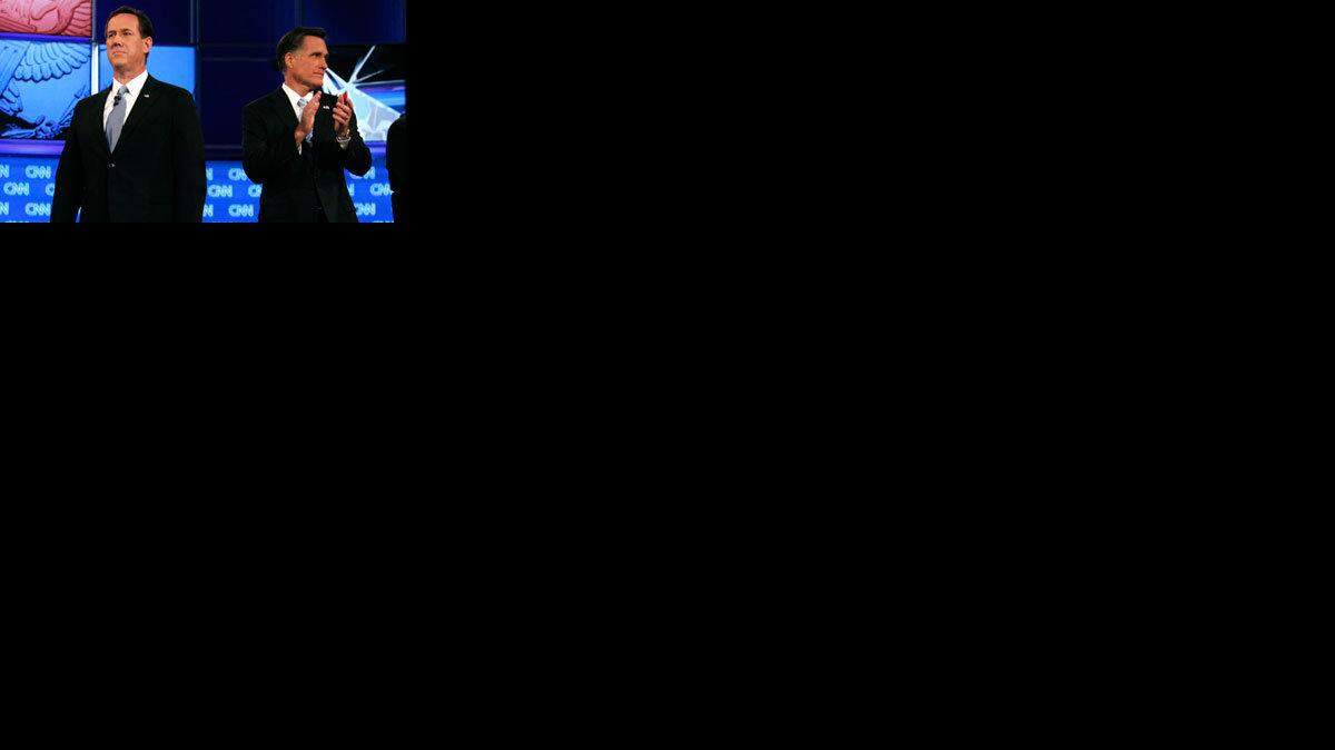 Rick Santorum, left, stands next to  Mitt Romney before the start of a Republican presidential debate