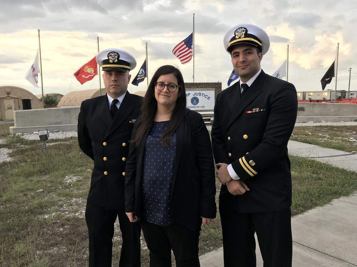 Pentagon paid attorney Susan Hensler, center, is the lead defense counsel for the former CIA captive charged as Abd al Hadi al Iraqi. At left is Navy Lieutenant Charles D. Ball III and at right is Navy Lieutenant Dahoud A. Askar, both detailed defense attorneys in the al-Qaida commander case. They pose at the Camp Justice sign at the U.S. Navy base at Guantánamo Bay, Cuba, in this image approved for release by a U.S. military officer.