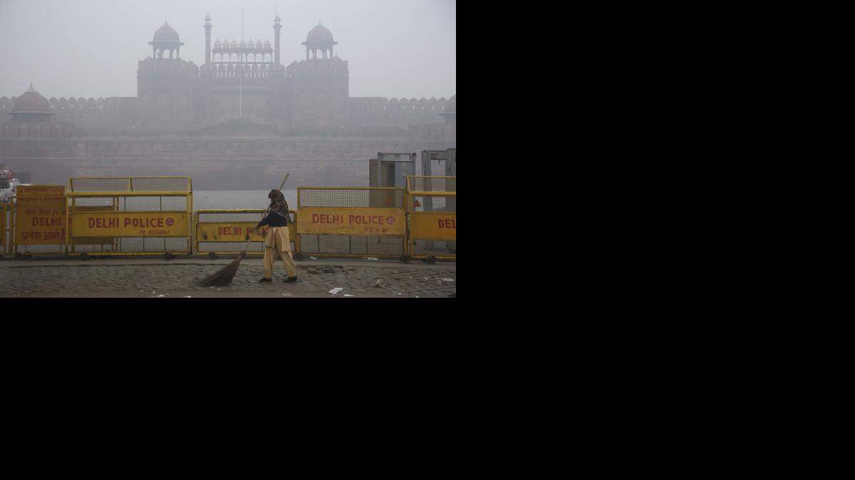 A woman sweeps the road in front of the Red Fort, which is barely visible through the smog in Delhi, India on Jan. 19, 2015. According to a World Bank report, shortened life spans of the urban population because of air pollution are costing India $18 billion annually.
