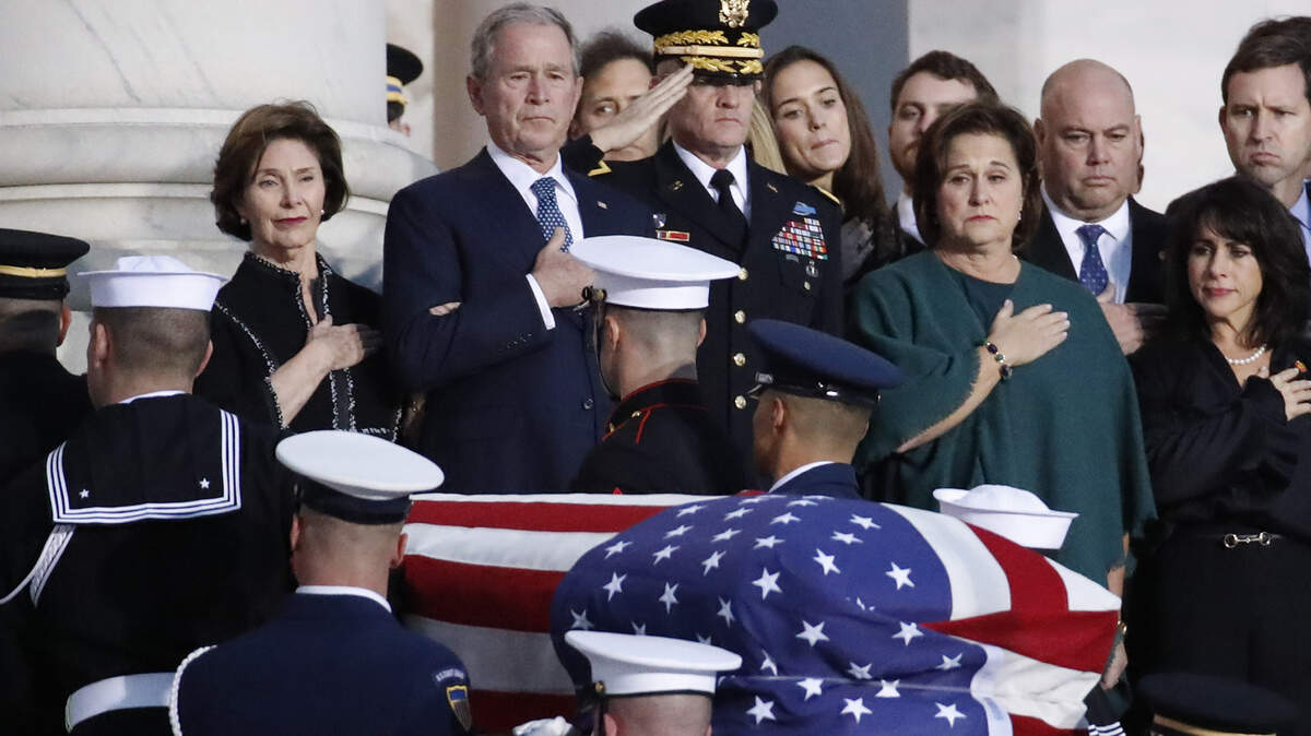 Former President George W. Bush, Laura Bush, left, and other family members watch as the flag-draped casket of former President George H.W. Bush is carried by a joint services military honor guard to lie in state in the rotunda of the U.S. Capitol, Monday, Dec. 3, 2018, in Washington.