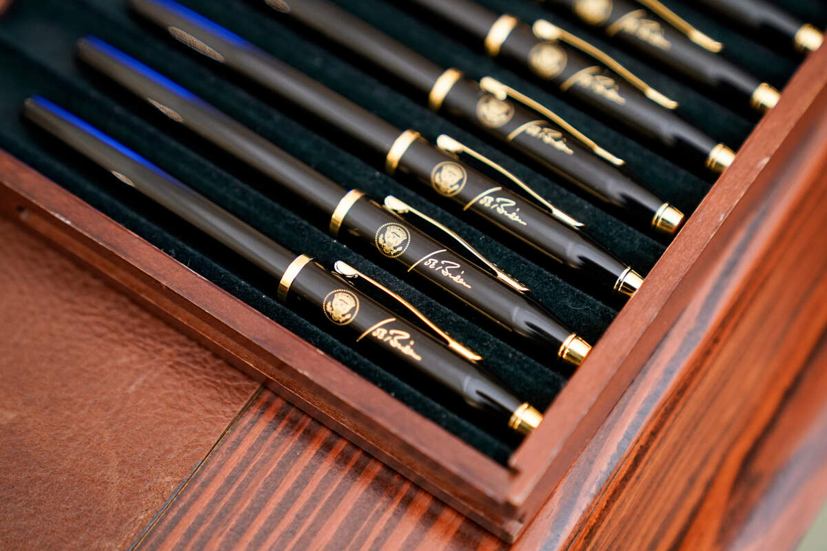 Pens featuring President Joe Biden’s signature and presidential seal, are displayed in the State Dinning Room of the White House, Thursday, Jan. 21, 2021, in Washington. (AP Photo/Alex Brandon)