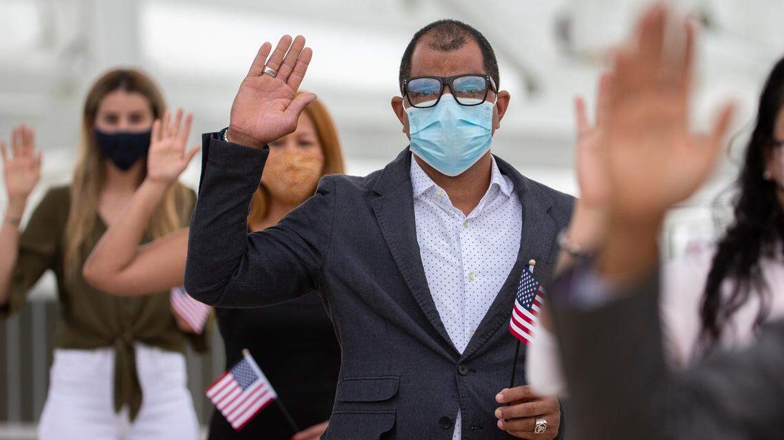 One of 51 Florida residents says the Pledge of Allegiance at a naturalization ceremony during halftime of an NFL football game between the Jacksonville Jaguars and the Cleveland Browns, Sunday, Nov. 29, 2020, in Jacksonville, Fla. This year’s participants originate from 24 countries spanning the globe. The Jaguars are the only team in the NFL to host a naturalization ceremony. (AP Photo/Stephen B. Morton)