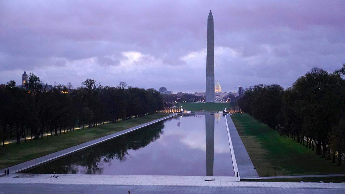 A man walks past the Lincoln Memorial Reflecting Pool and Washington Monument as sunrise approaches on Thanksgiving, Thursday, Nov. 26, 2020, in Washington. The Presidential Inauguration Committee will host a memorial for COVID-19 victims at the reflecting pool the day before President-elect Joe Biden’s inauguration. (AP Photo/Patrick Semansky)