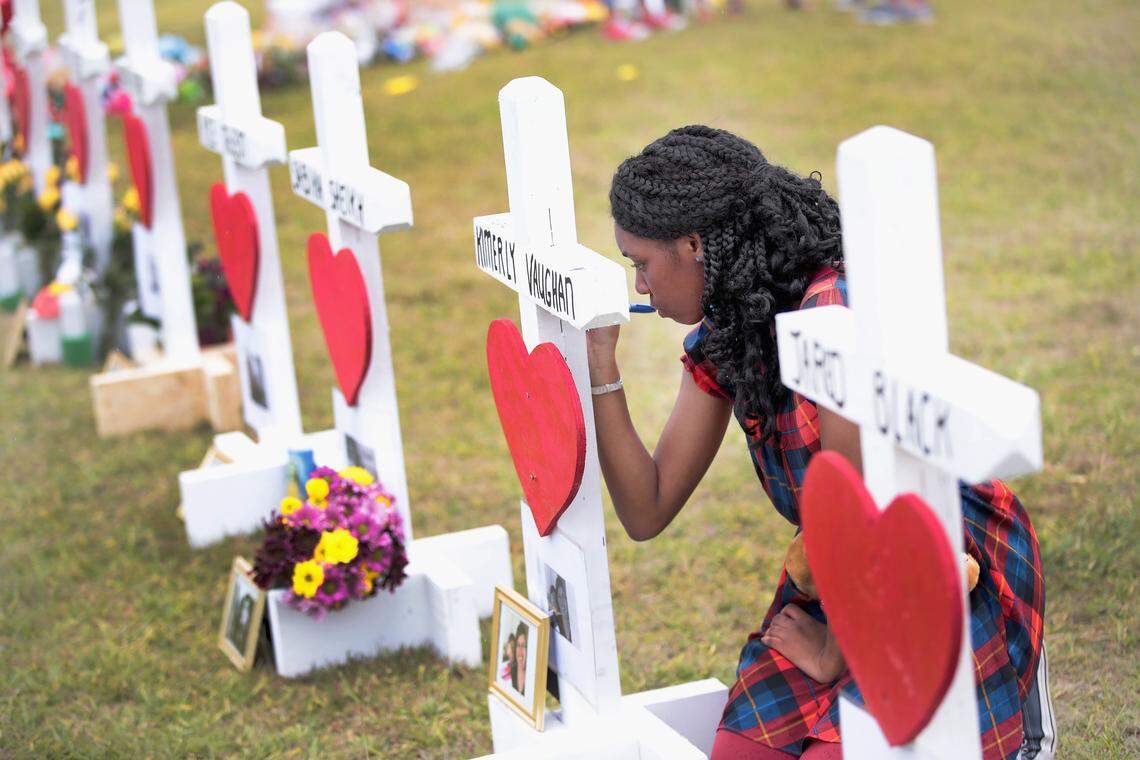 Jai Gillard, a freshman at Santa Fe High School in Texas, leaves a message on a cross, one of 10 placed in front of the school in honor of the eight students and two teachers killed by a 17-year-old classmate on May 18, 2018, three months after Parkland.