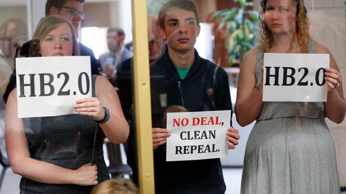 Opponents of a proposed replacement for House Bill 2 hold protest signs outside a room where supporters of the proposal held a press conference at the N.C. General Assembly in Raleigh, NC on Feb. 28, 2017.