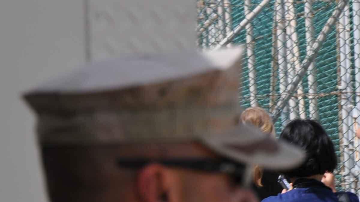 A detainee can be seen beyond the fence at Guantanamo's Camp 4 in September. U.S. military often brought visitors to Guantanamo to the camp to see and photograph detainees. The camp was closed in January for renovation. This photo was approved for publication by U.S. military censors.