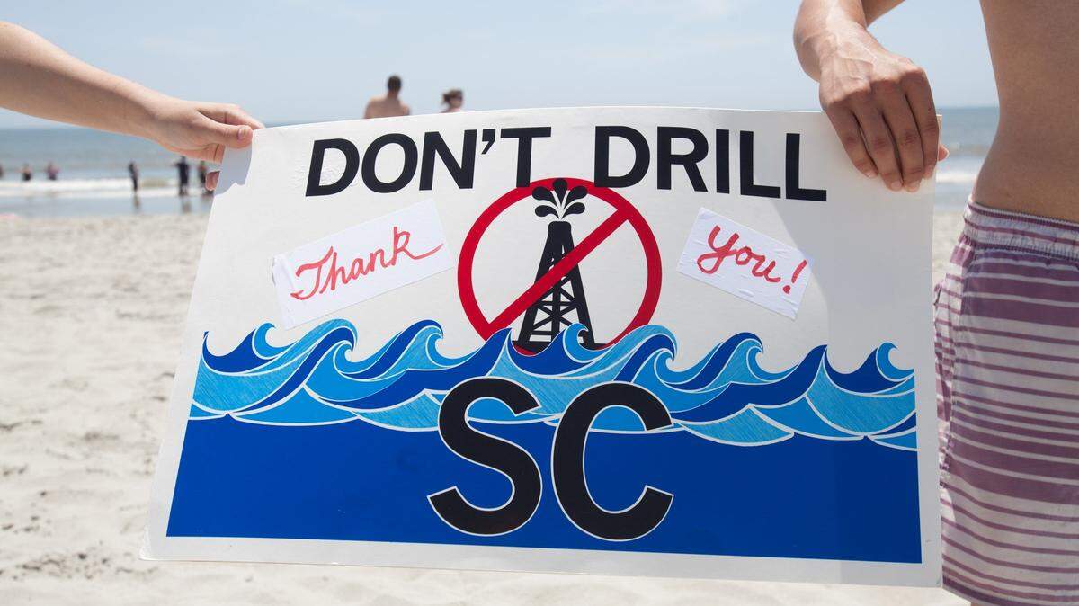 Groups that oppose Atlantic oil drilling have held protests up and down the coast since the Trump administration advanced plans for oil exploration in the region. Here, protestors hold a sign in Myrtle Beach, South Carolina at the annual Hands Across the Sand event in 2017.