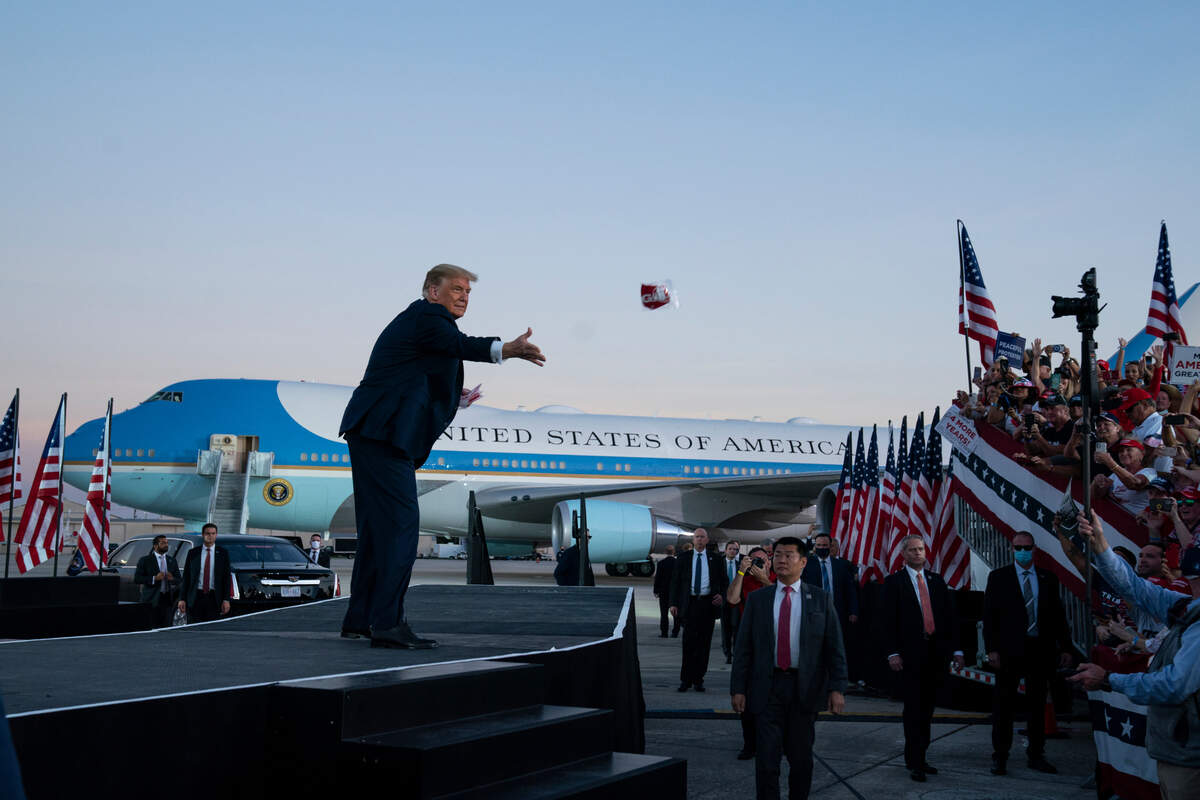 President Donald Trump tosses face masks into the crowd as he arrives for a campaign rally at Orlando Sanford International Airport, Monday, Oct. 12, 2020, in Sanford, Fla. (AP Photo/Evan Vucci)