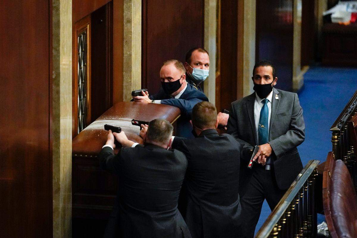 U.S. Capitol Police with guns drawn stand near a barricaded door as rioters try to break into the House Chamber at the U.S. Capitol on Wednesday, Jan. 6, 2021, in Washington. (AP Photo/Andrew Harnik)
