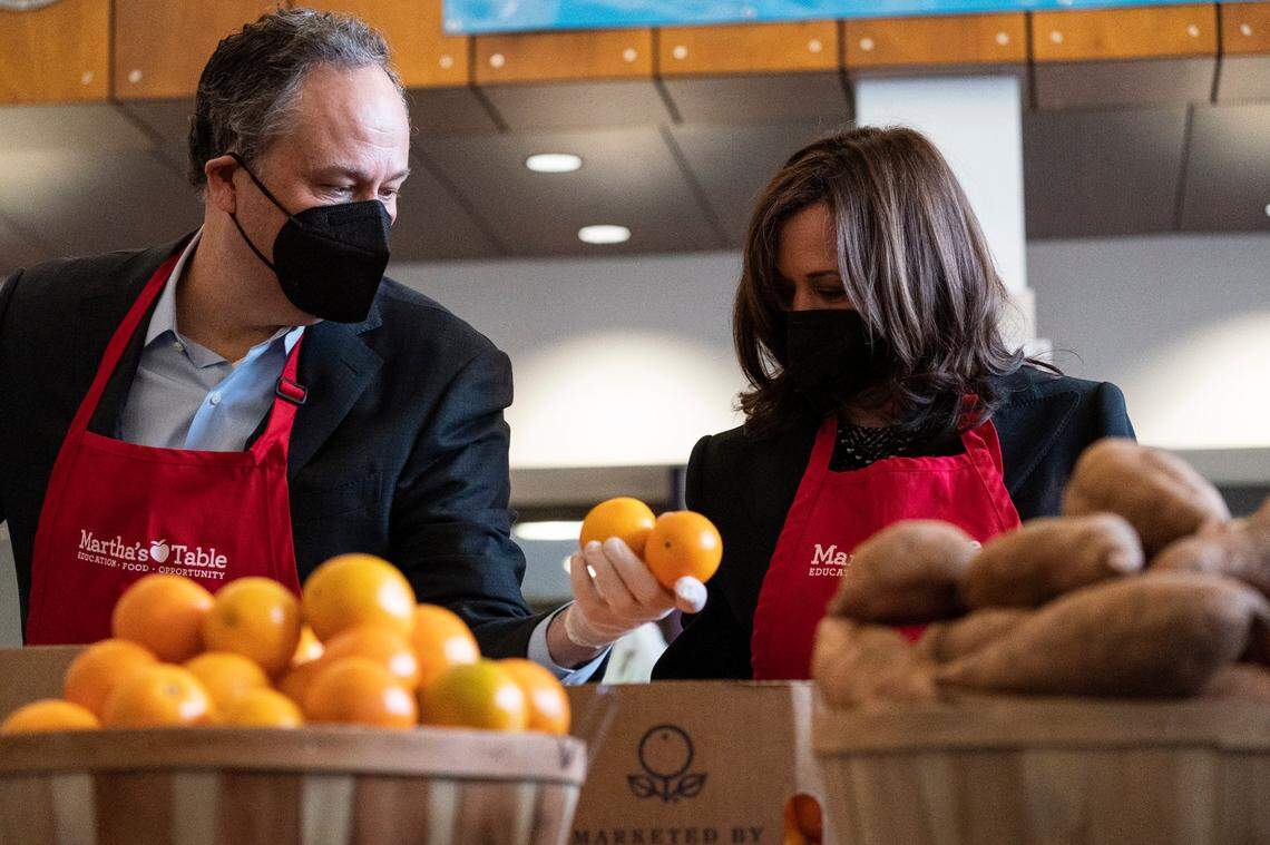 Vice President Kamala Harris, right, with her husband Doug Emhoff, fills bags with fruit and other items, at Martha’s Table, Monday, Jan. 17, 2022, in Washington.