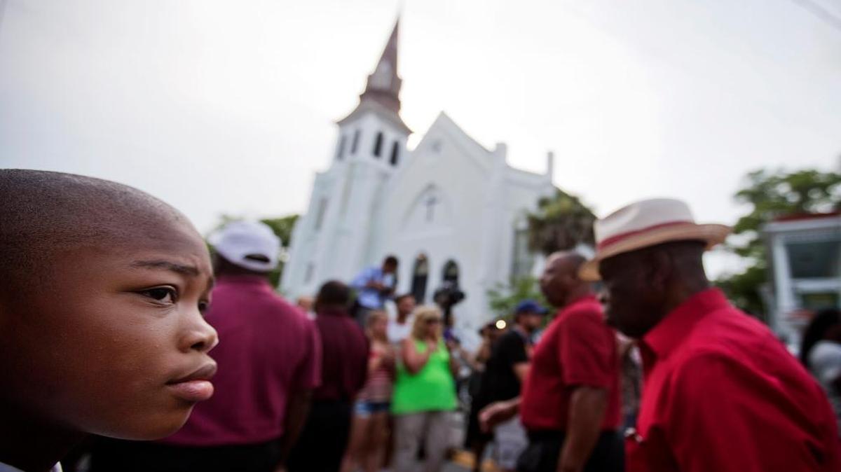 Malik McCarthan, 11, of Hardeeville, S.C., watches as a group passes by singing as the wake for Sen. Clementa Pinckney, one of the nine killed in last week's mass shooting, takes place inside Emanuel AME Church, seen in the background, June 25, 2015, in Charleston, S.C.