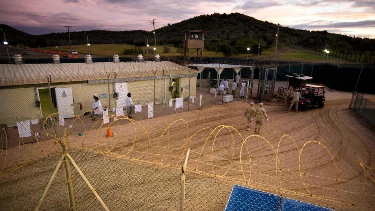 Guantánamo detainees, in white, and U.S. military guards walk around the Camp 4 detention facility in this Nov 18, 2008 file photo.