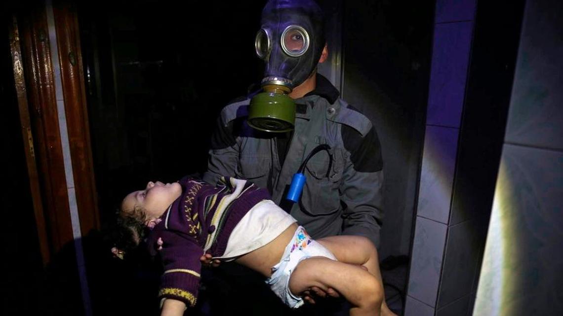 This April. 8, 2018 image released by the Syrian Civil Defense White Helmets, shows a rescue worker carrying a child following an alleged chemical weapons attack in the rebel-held town of Douma, near Damascus, Syria.