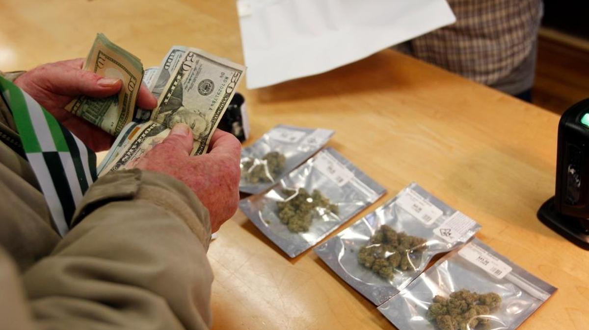 A customer purchases marijuana at Harborside marijuana dispensary on Monday in Oakland, Calif. On New Year’s Day recreational marijuana could be sold legally in California, but an announcement by Attorney General Jeff Sessions could disrupt the market.