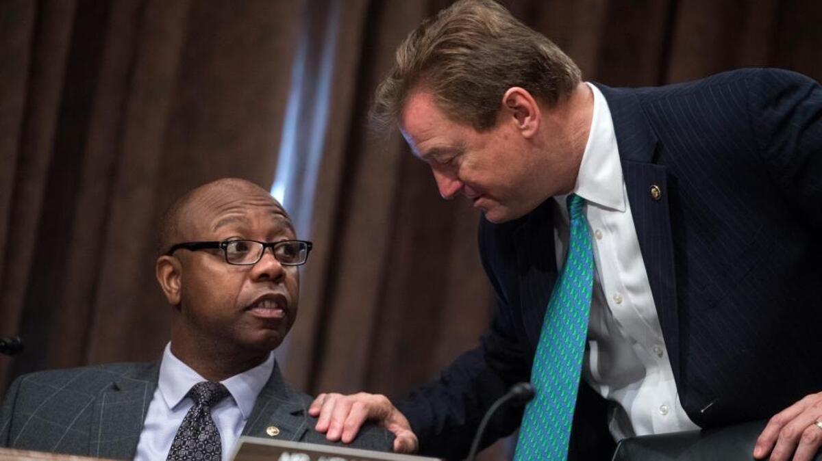 Sen. Tim Scott, R-S.C., left, and Dean Heller, R-Nev., talk during a Senate Banking, Housing and Urban Affairs Committee hearin.