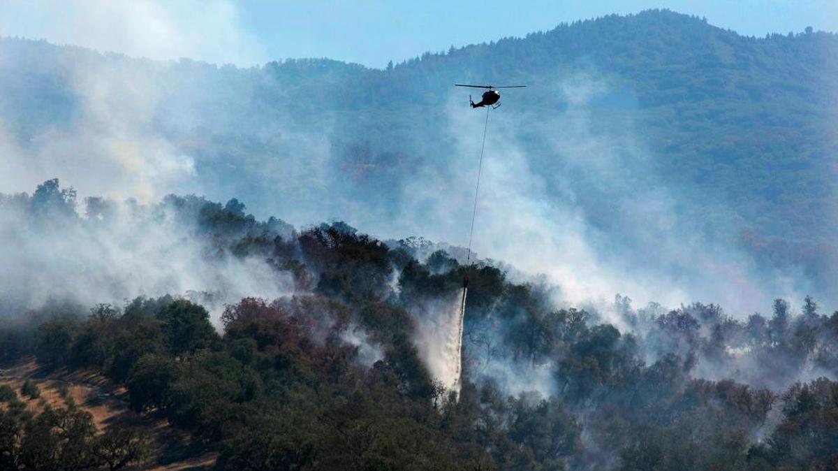 
A helicopter makes a water drop on a wildfire hot spot Sunday, Sept. 20, 2015, in Carmel Valley, Calif. President Barack Obama issued a major disaster declaration for California on Tuesday.
