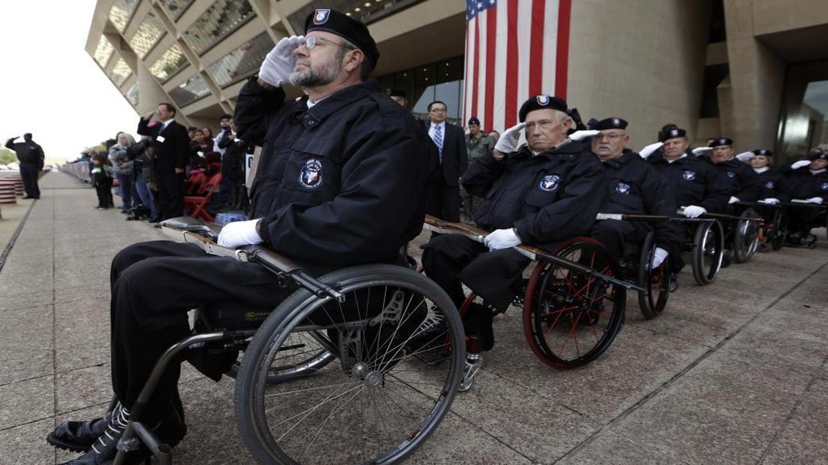 John Fay, left, leads a line of fellow honor guards from the Lone Star Chapter of the Paralyzed Veterans of American during the Pledge of Allegiance before a Veterans Day parade in downtown Dallas on Nov. 11, 2014.